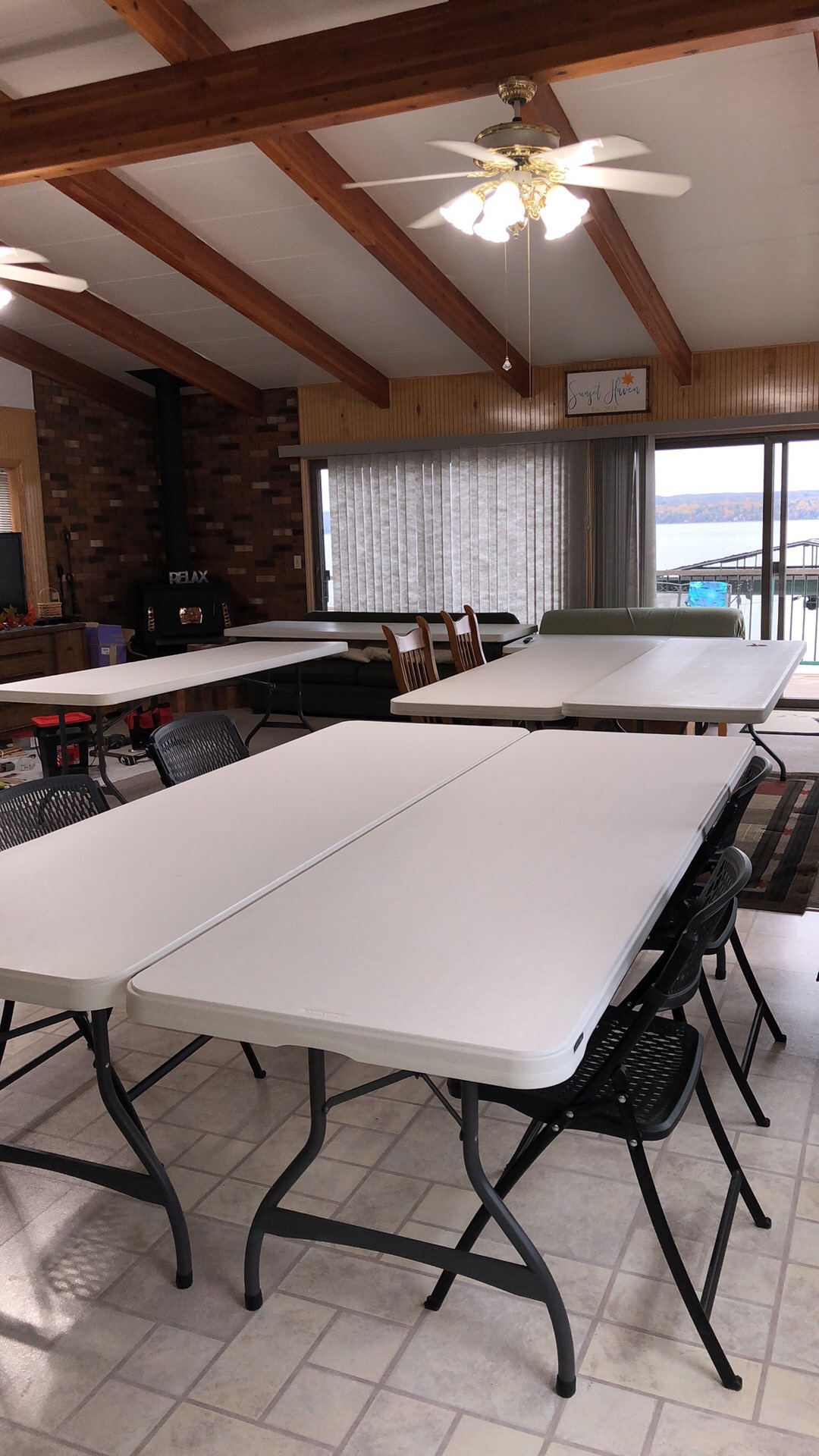 White crafting tables in the lakefront room, with Cayuga Lake visible through the windows